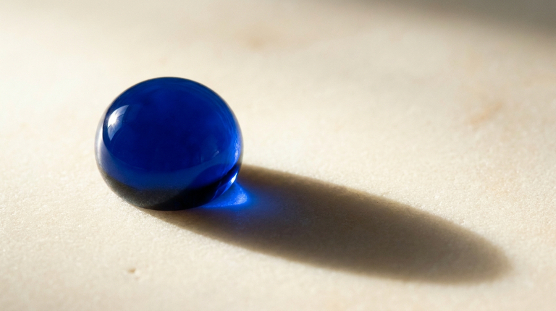 A single drop of blue serum beaded on a pale stone surface